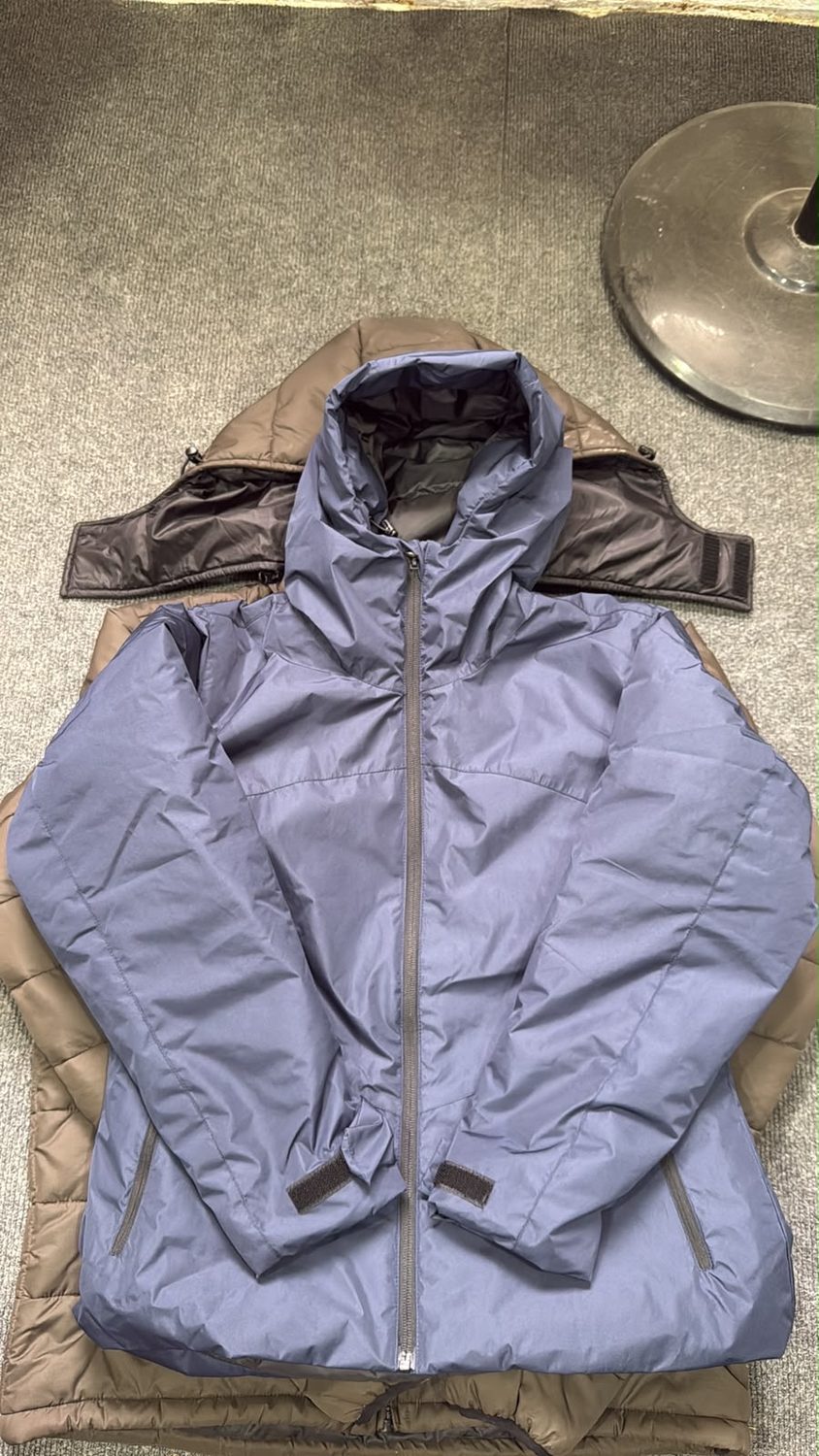 A periwinkle blue insulated hooded jacket laid over a brown lined jacket