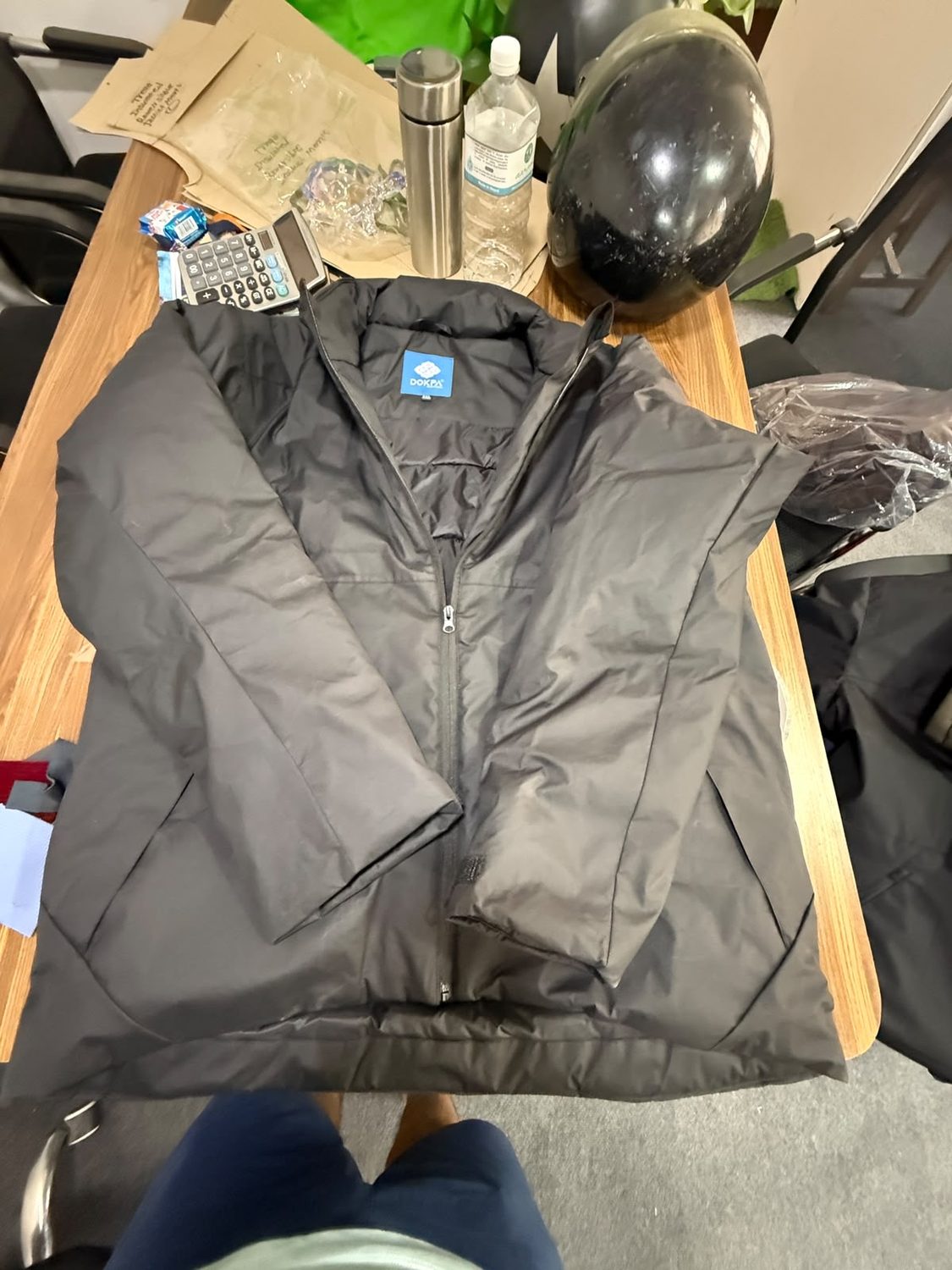 A dark grey jacket opened on a workroom desk showing the blue Dokpa label